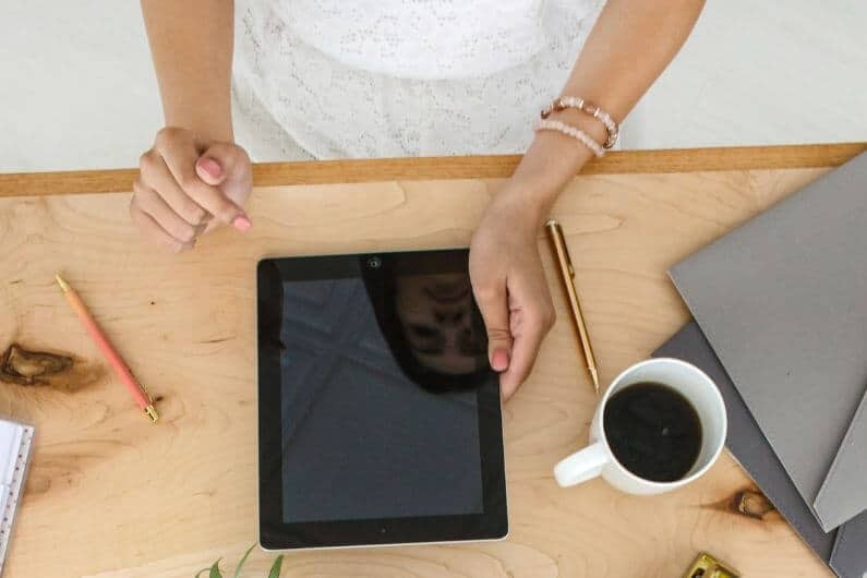 Woman working at desk with a tablet and coffee mug