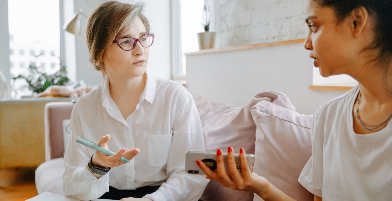 Two women sitting on a coach discussing how to drive traffic to their websites